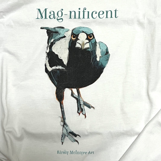 White t-shirt with an australian native magpie bird original illustration by artist Kirsty McIntyre and the word 'Mag-nificent' above it, on a white background.