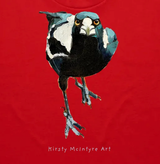 Bird illustration on a red background with 'Kirsty McIntyre Art' text - closeup of tshirt featuring an original staring, fierce magpie graphic design by Kirsty McIntyre, australian bird lover and artist