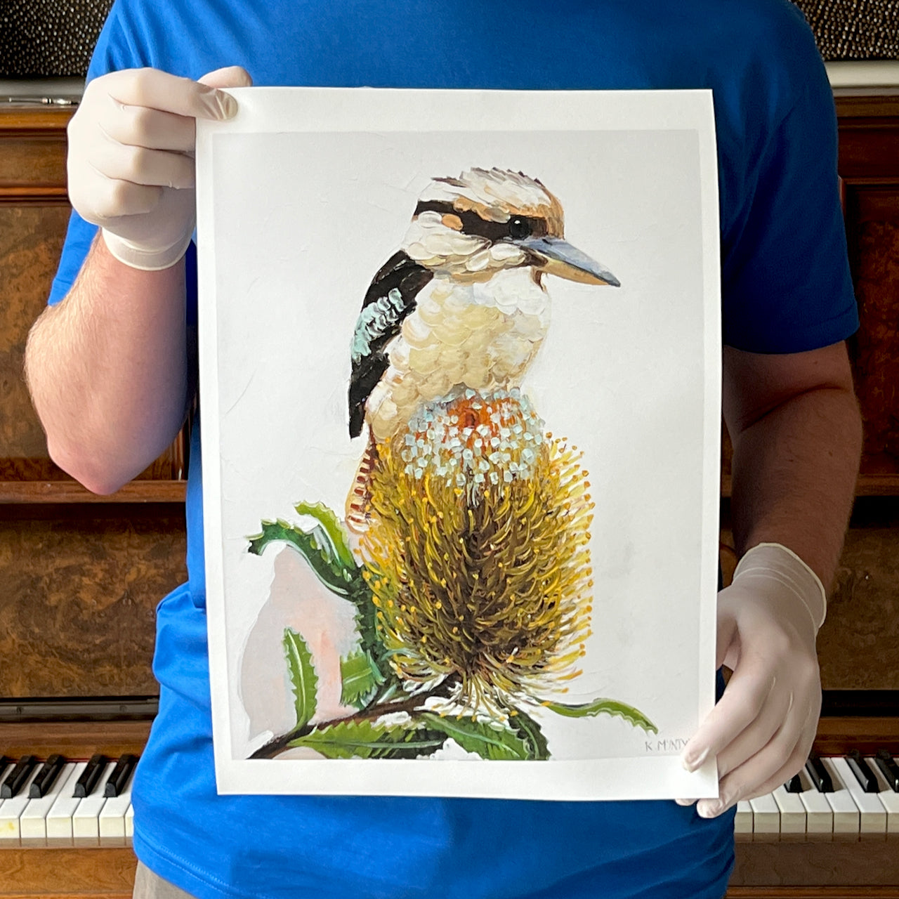Person holding a painting of a kookaburra on a white sheet;available as a giclee print or reproduction iof an original design by Australian artist, Kirsty McIntyre