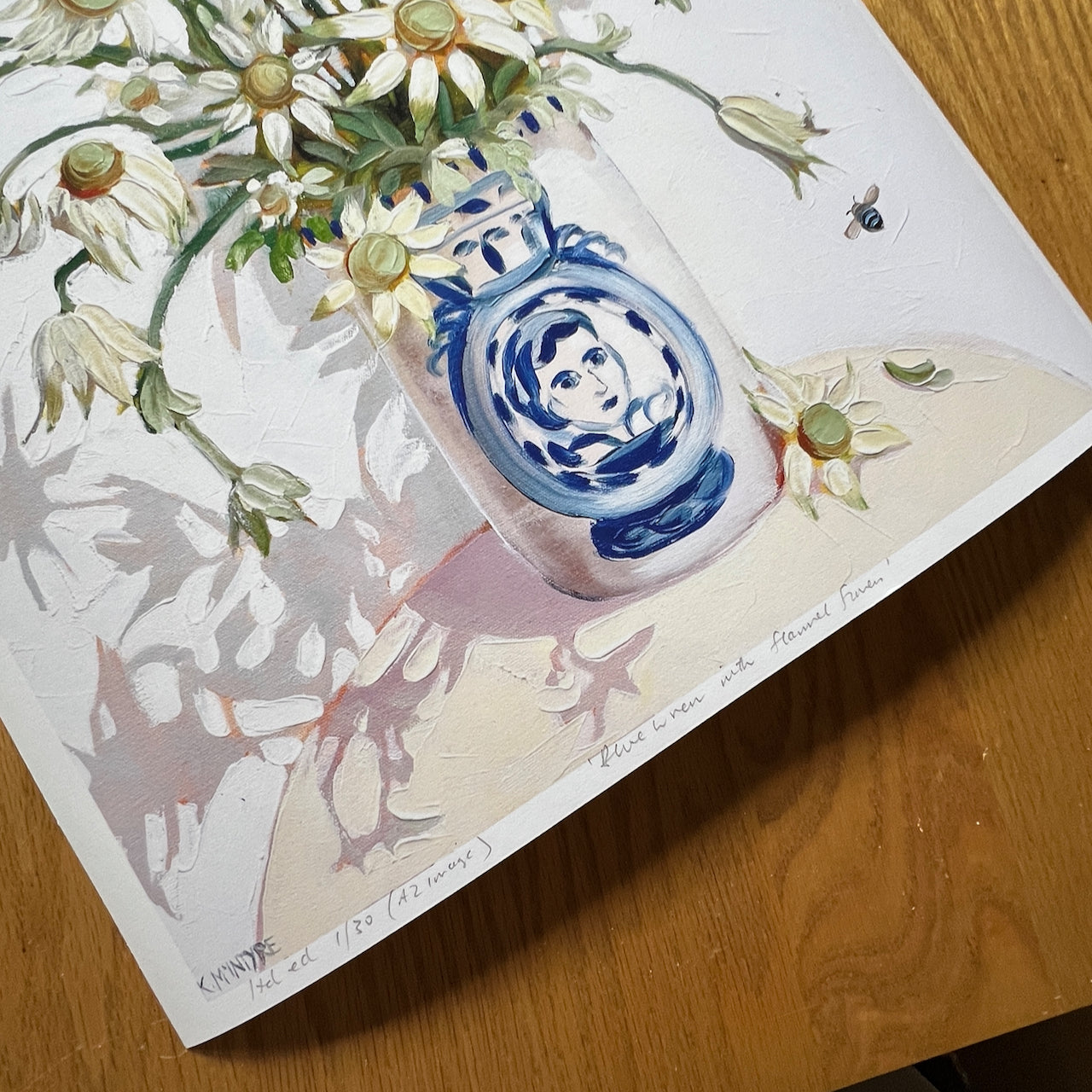 Artistic depiction of a vase with floral design on a wooden surface detail of an original blue wren, emu wren and flannel flower australian bird design in a giclee reproduction print by Australian bird artist, Kirsty Mcintyre