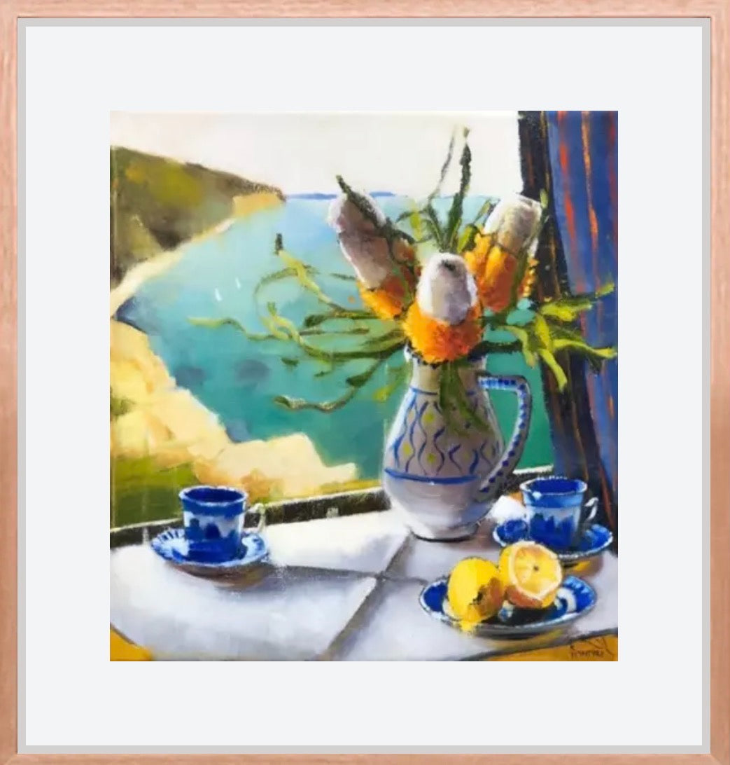 Framed artwork of a still life scene with a vase of flowers, cups, and lemons on a table. "Banksia Bay" is a giclee print of an original artwork by Australian artist, Kirsty McIntyre