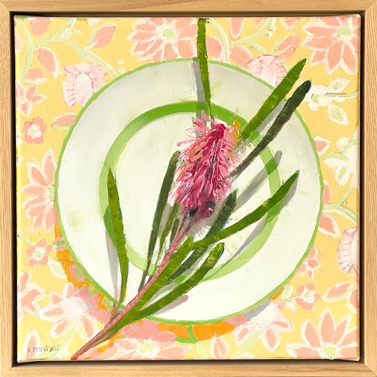 Framed artwork of a pink flower with green leaves on a yellow floral background