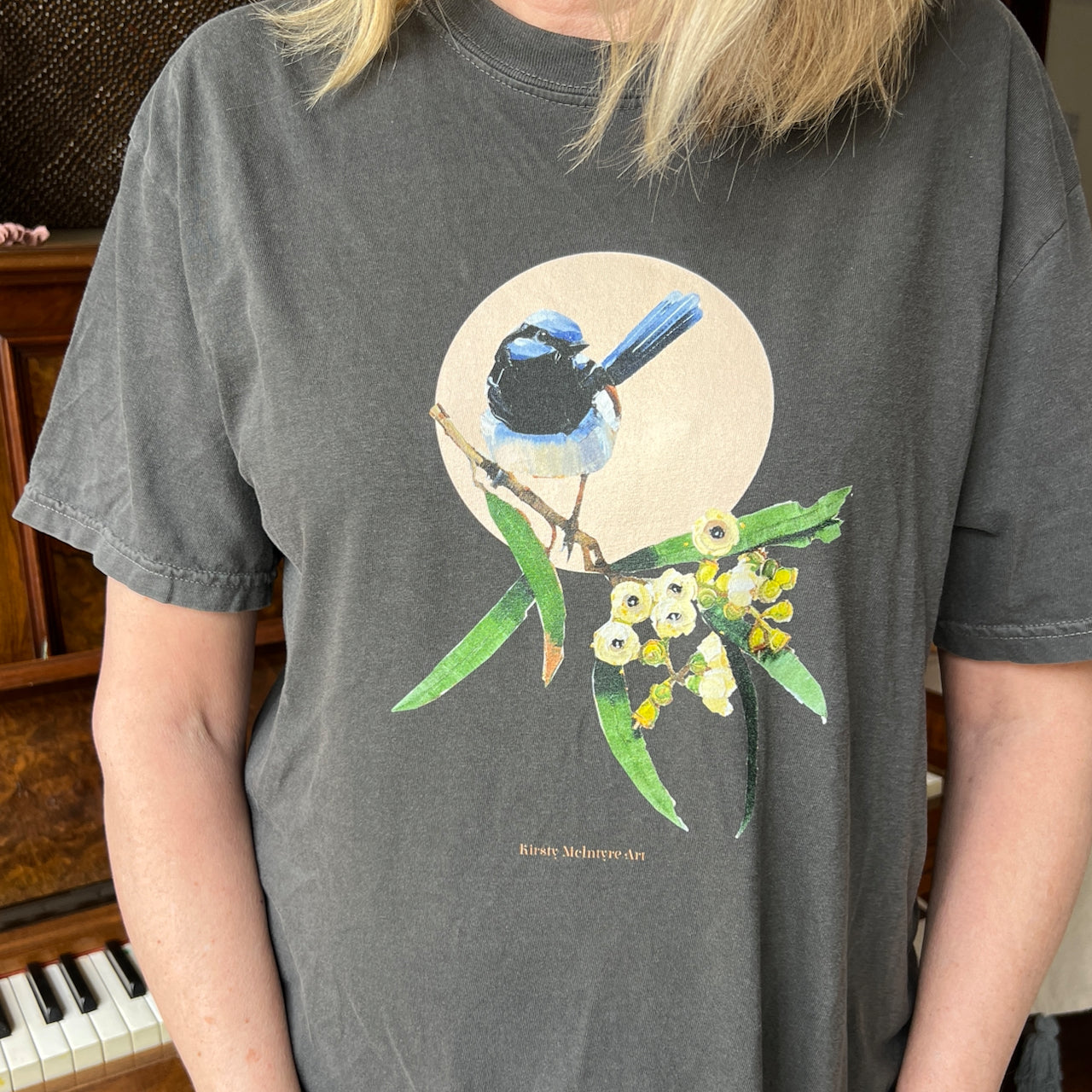 Person wearing a dark gray t-shirt with a blue wren bird and floral original design. by kirsty mcintyre