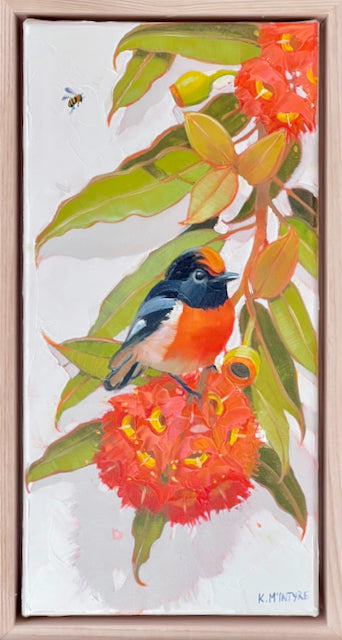 A framed painting of a small bird red robin perched on a flowering bush branch, with green leaves, bright orange-red blossoms, and a pale background. The artwork is shown within a light wood frame.