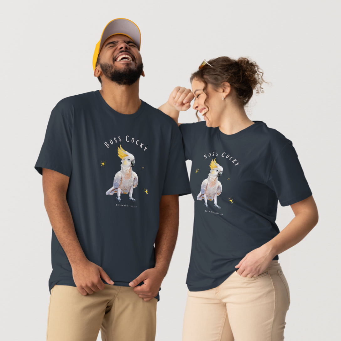 Two people wearing matching t-shirts with a graphic design on a plain background.Person wearing a navy blue t-shirt with a parrot graphic and text 'Boss Cocky' on a white background. Original cockatoo tshirt design by artist, Kirsty McIntyre, australian.